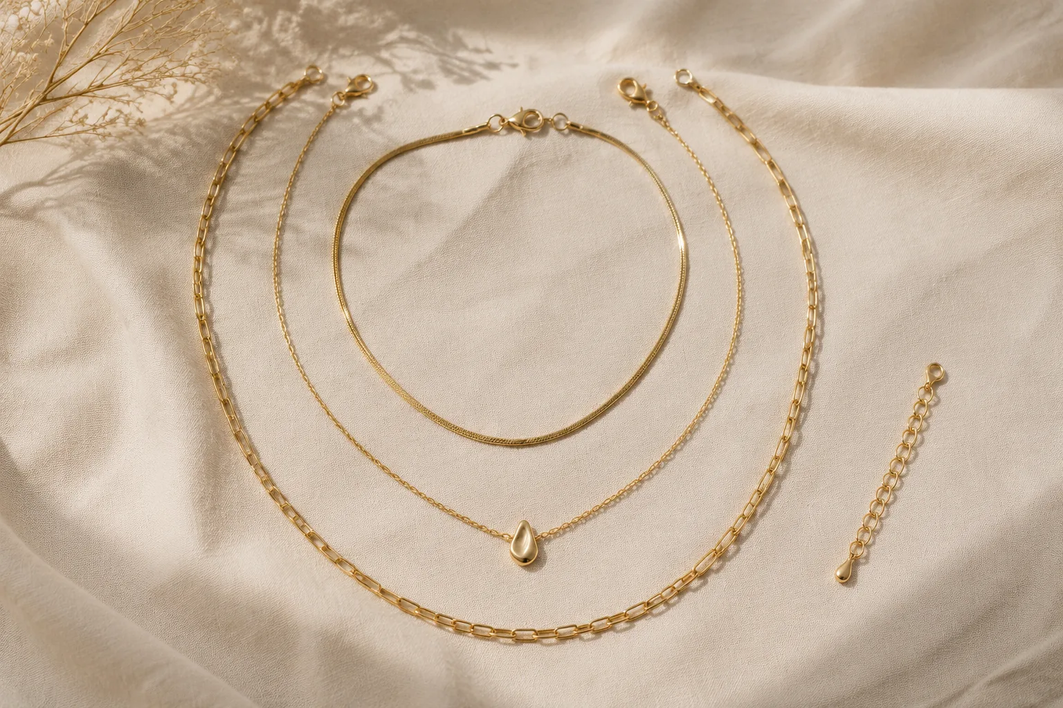 Three unbranded necklaces arranged in separated lengths on neutral linen.