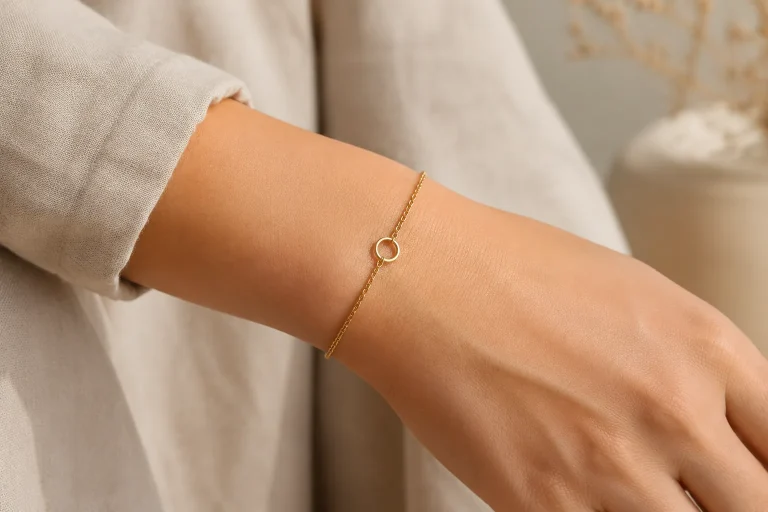 A close view of a delicate unbranded yellow-gold chain bracelet on an adult wrist, illustrating the everyday scale and permanent-style fit discussed in the guide to 9K welded jewelry.