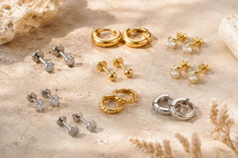 A careful arrangement of titanium studs, solid gold hoops, silver earrings, and plated fashion pieces helps readers compare jewelry materials before buying.